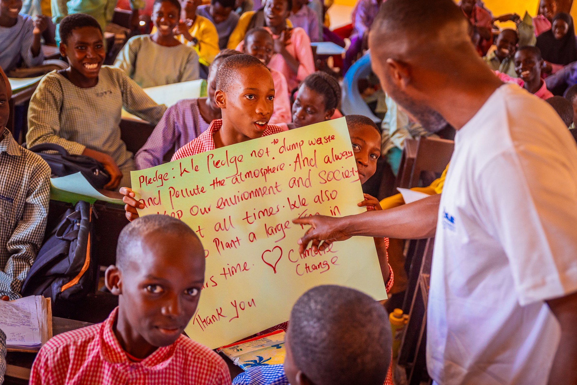 Student holding a handwritten climate pledge during a Climate Club session
